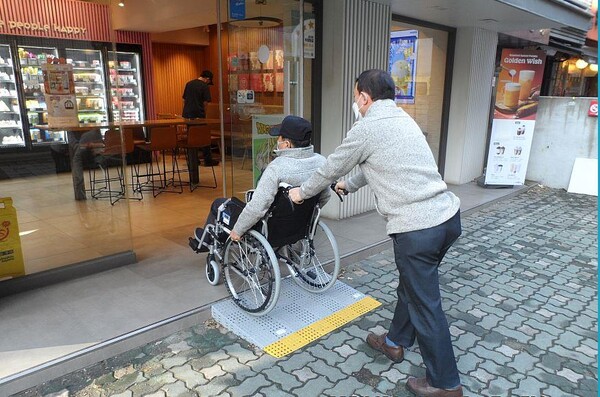 휠체어를 이용하는 주민이 경사로를 통해 가게 입구로 들어가고 있다. 사진=성동구