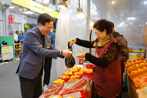 진교훈 구청장(왼쪽)이 25일 설 명절을 앞두고 화곡중앙시장을 찾아 과일을 구매하고 있다. 사진=강서구